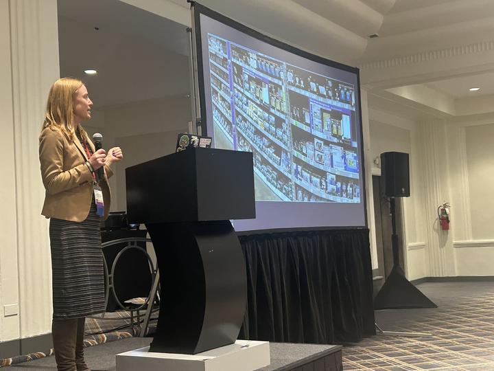 Heather Boughton presenting in front of a lightbulb shelf presentation