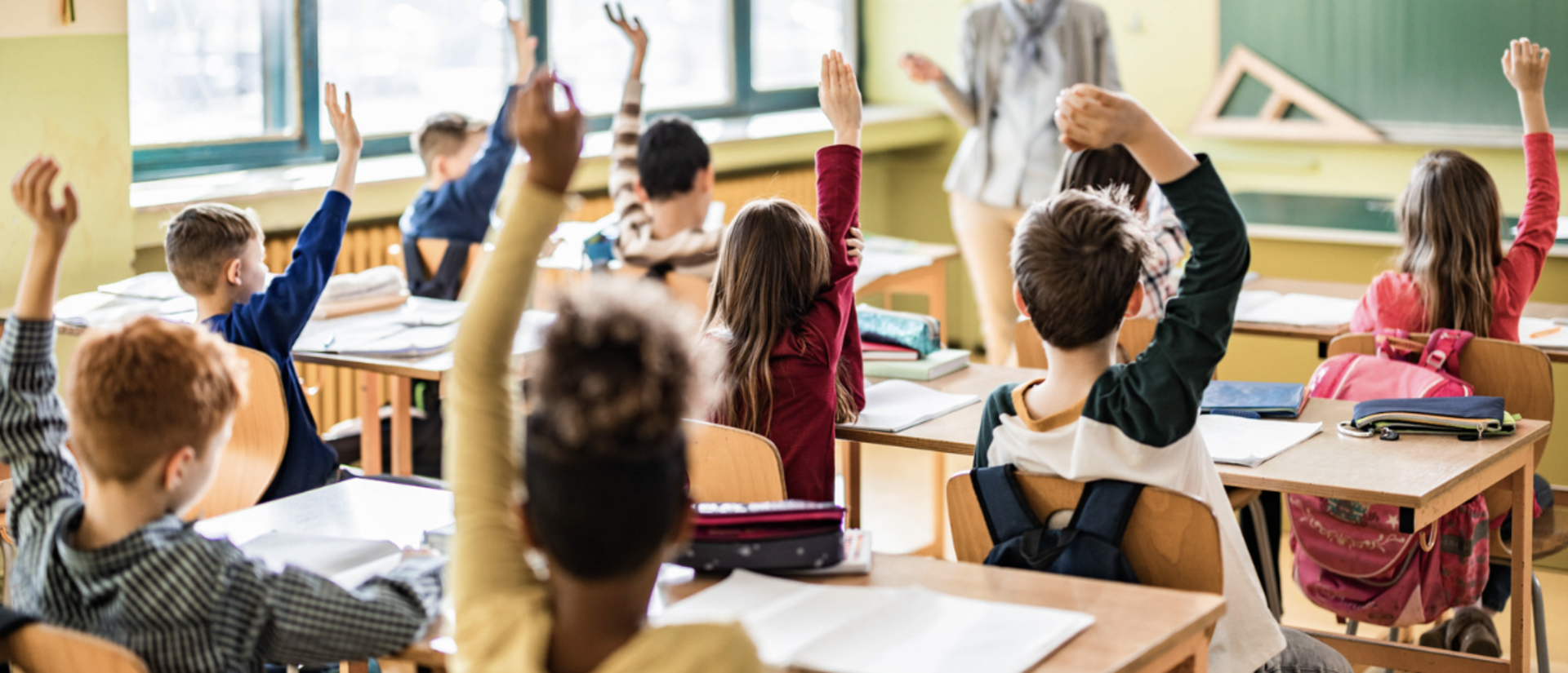Students in classroom raising hands